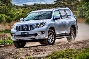 An SUV is driving on a dirt road